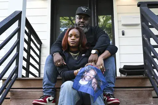 Reggie Cunningham, top, and his wife Ferguson activist Brittany Packnett-Cunningham pose for an image while holding a handkerchief with picture of her father Rev. Ronald Packnett and Brittany, Saturday, Sep. 7, 2024, in Mount Rainier, Md. (AP Photo/Terrance Williams)