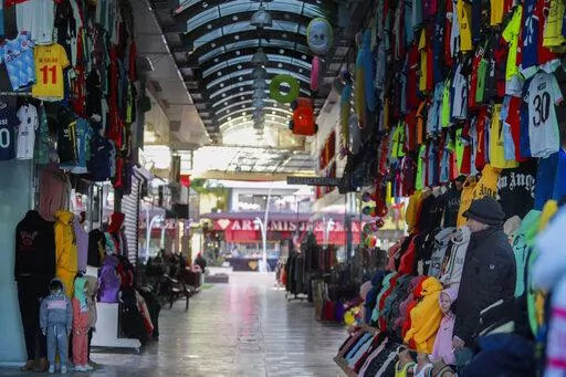A clothes shop keeper waits for clients in a deserted tourist shopping area in Belek, Antalya, Turkey, Saturday, March 12, 2022. After losing two years to the COVID-19 pandemic, shopkeepers in the heart of the Turkish Riviera had hoped for a strong tourism season this year to help keep their businesses afloat. But Russia's war in Ukraine is fast dampening their spirits. (AP Photo/Riza Ozel)