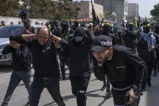 Palestinian gunmen shoot in the air during the funerals for Sanad Abu Atiyeh, 17 and Yazid al-Saadi, 23, in the West Bank refugee camp of Jenin, Jenin, Thursday, March 31, 2022. Israeli forces raided a refugee camp in the occupied West Bank early Thursday, setting off a gun battle in which two Palestinians were killed and 15 were wounded, the Palestinian Health Ministry said. (AP Photo/Nasser Nasser)