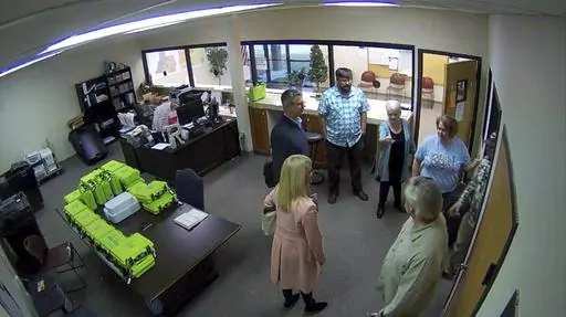 This Jan. 7, 2021, image taken from Coffee County, Ga., security video, appears to show Cathy Latham (center, long turquoise top), introducing members of a computer forensic team to local election officials. Latham was the county Republican Party chair at the time. The computer forensics team was at the county elections office in Douglas, Ga., to make copies of voting equipment in an effort that documents show was arranged by attorney Sidney Powell and others allied with then-President Donald Tr