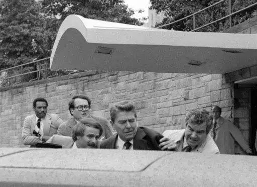 President Ronald Reagan waves and then looks up before being shoved into the President's limousine by secret service agents after being shot outside a Washington hotel, March 30, 1981. The assassination attempt of former President Donald Trump has parallels to the last time a president or presidential candidate was wounded — in 1981 when Ronald Reagan was nearly killed by an assailant's bullet. Reagan's life was spared thanks to the quick actions of a Secret Service agent and the skill of doct