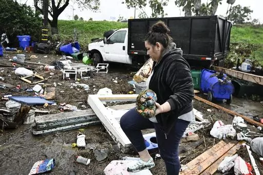 Marlene Sanchez-Barriento salavages items behind her home damaged by flooding, Tuesday, Jan. 23, 2024, in. Sanchez-Barriento's home was damaged when flood waters rushed though her home on Monday, Jan. 23. (AP Photo/Denis Poroy)