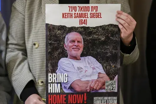 Tal Wax poses in Madrid on Thursday, Jan. 25, 2024, with a poster showing her uncle Keith Siegel, an Israeli-American hostage held in Gaza since the Oct. 7 attacks by Hamas. (AP Photo/Manu Fernandez, File)