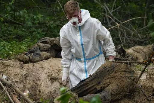 A member of an extraction crew works during an exhumation at a mass grave near Bucha, on the outskirts of Kyiv, Ukraine, Monday, June 13, 2022. (AP Photo/Natacha Pisarenko)