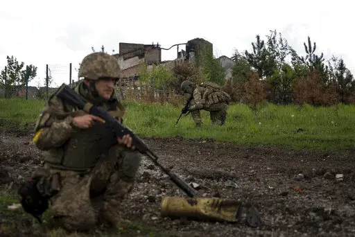 Ukrainian servicemen squat during a patrol in a recently retaken village, north of Kharkiv, east Ukraine, Sunday, May 15, 2022. (AP Photo/Mstyslav Chernov)