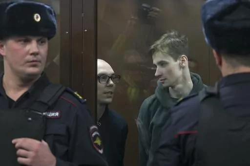 Artyom Kamardin, left, and Yegor Shtovba, right, stand behind a glass in a cage in a courtroom in Moscow, Russia, Thursday, Dec. 28, 2023. Artyom Kamardin was given a 7-year prison sentence Thursday for reciting verses against Russia's war in Ukraine, a tough punishment that comes during a relentless Kremlin crackdown on dissent. Yegor Shtovba, who participated in the event and recited Kamardin's verses, was sentenced to 5 1/2 years on the same charges. (AP Photo, File)