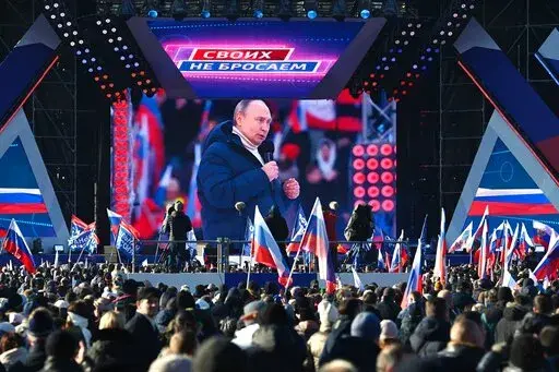 Russian President Vladimir Putin seen on the big screen as he delivers his speech at the concert marking the eighth anniversary of the referendum on the state status of Crimea and Sevastopol and its reunification with Russia, in Moscow, Russia, Friday, March 18, 2022, with a banner reading "For Russia" projected in the backgroud. (Vladimir Astapkovich/Sputnik Pool Photo via AP)