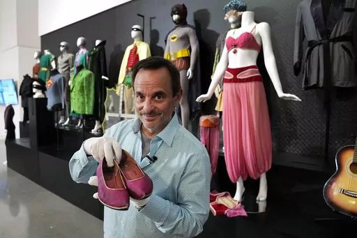 James Comisar holds a pair of shoes once used by actor Barbara Eden in the television show, "I Dream of Jeannie", Thursday, April 27, 2023, in Irving, Texas. A dizzying number of props, sets, and costumes from television shows beloved by generations of viewers will be sold at auction next month. The collection James Comisar has spent over 30 years amassing includes "The Tonight Show" set Johnny Carson gave him after retiring, the timeworn living room from "All in the Family," and the bar where S
