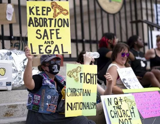 A small group, including Stephanie Batchelor, left, sits on the steps of the Georgia state Capitol protesting the overturning of Roe v. Wade on June 26, 2022. A trial to determine whether Georgia can continue to ban abortion as early as six weeks into a pregnancy is set to begin in an Atlanta courtroom on Monday, Oct. 24, 2022. (AP Photo/Ben Gray, File)