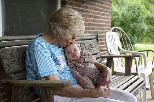 Tressie Corsi sits with her great great granddaughter Amelia Hollis on the porch of the house she has owned in Johnstown, Ohio, since 1972 to that she is giving up to make way for an Intel manufacturing plant during an interview Monday, June 20, 2022. Corsi and her husband raised four children and welcomed multiple generations of grandchildren and great-grandchildren, including some who lived right next door. (AP Photo/Paul Vernon)