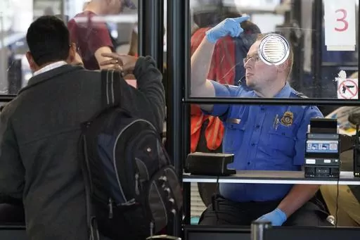 A Transportation Security Administration agent signals for the next airline passenger in line at a security checkpoint in Chicago's O'Hare International Airport Friday, May 26, 2023. On Aug. 25, The Associated Press reported on stories circulating online incorrectly claiming TSA managers were told on Aug. 15 that by mid-September they, along with airport employees, will again be required to wear face masks and by mid-October the policy will apply to travelers as well. (AP Photo/Charles Rex Arbog