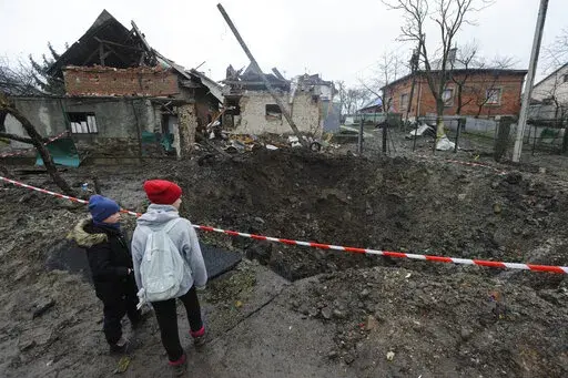 Children look at a crater created by an explosion in a residential area after Russian shelling in Solonka, Lviv region, Ukraine, Wednesday, Nov. 16, 2022. (AP Photo/Mykola Tys)