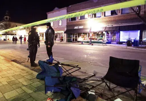Police stand near toppled chairs lining W. Main St. in downtown Waukesha, Wis., after an SUV drove into a parade of Christmas marchers, Sunday, Nov. 21, 2021.  The trial of Darrell Brooks Jr.  accused of driving his SUV through a Christmas parade in suburban Milwaukee, killing six people and wounding many more, was never going to be easy for the people who lived through it. Now it may be worse, after Brooks Jr. was allowed to dismiss his attorneys and represent himself.  (John Hart/Wisconsin Sta