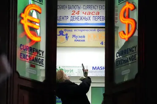 A woman stands in a currency exchange office in St. Petersburg, Russia, on Feb. 25, 2022. Russia plans to reopen its stock market for limited trading on Thursday, march 24, 2022, nearly one month after shares plunged and the exchange was shut down following the invasion of Ukraine. (AP Photo/File)