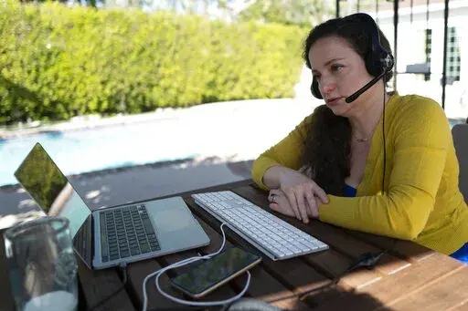 Julia Entin sits at her computer at her backyard office, coordinating efforts to rescue Holocaust survivors in Ukraine, Monday, March 14, 2022, in Los Angeles. (AP Photo/Richard Vogel)