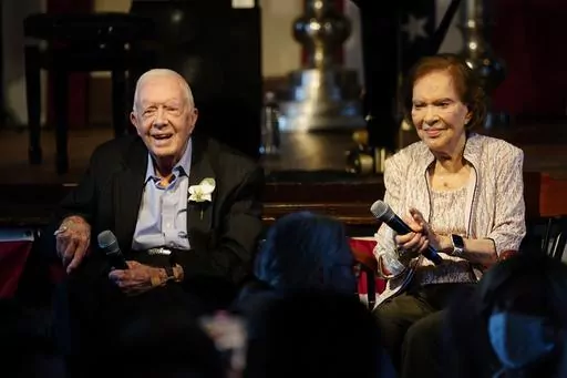 FILE- Former President Jimmy Carter and his wife former First Lady Rosalynn Carter sit together during a reception to celebrate their 75th anniversary Saturday, July 10, 2021, in Plains, Ga. In the year since Jimmy Carter first entered home hospice care, the 39th president has celebrated his 99th birthday, enjoyed tributes to his legacy and outlived his wife of 77 years. Rosalynn Carter, who died in November 2023 after suffering from dementia, spent just a few days under hospice. (AP Photo/John 