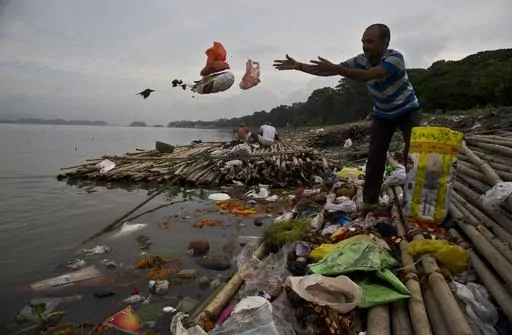 A Hindu devotee throws flowers and plastic bags into river Brahmaputra in Gauhati, India, Wednesday, Oct. 9, 2019. Negotiators from around the world gather at UNESCO in Paris on Monday, May 29, 2023, for a second round of talks aiming toward a global treaty on fighting plastic pollution in 2024. (AP Photo/Anupam Nath, File)