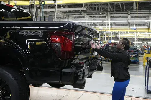 Assembly line worker Lashunta Harris applies the Ford logo on a 2024 Ford F-150 truck being assembled at the Dearborn Truck Plant, April 11, 2024, in Dearborn, Mich. On Friday, June 5, 2024, the U.S. government issues its June jobs report. (AP Photo/Carlos Osorio, File)
