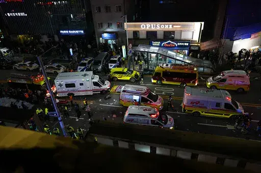 Ambulances and rescue workers arrive at the street near the scene of a crowd surge in Seoul, South Korea, Sunday, Oct. 30, 2022. Witnesses say the nightmarish scene intensified as people performed CPR on the dying and carried limp bodies to ambulances, while dance music pulsed from garish clubs lit in bright neon. Others tried desperately to pull out those who were trapped underneath the crush of people, but failed because too many in the crowd had fallen on top of them. (AP Photo/Lee Jin-man)