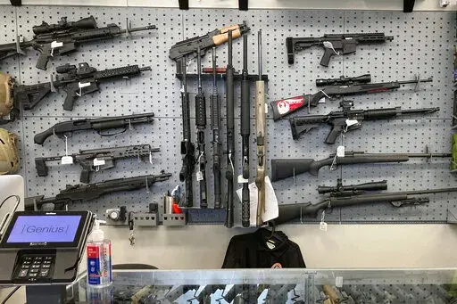 Firearms are displayed at a gun shop in Salem, Ore., on Feb. 19, 2021. A federal judge in Portland, Ore., ruled Tuesday, Dec. 6, 2022, that a new voter-passed ban on high-capacity gun magazines can go into effect Thursday, Dec. 8, but placed a 30-day hold on a permit-to-purchase requirement after local and state law enforcement agencies said they could not have a permitting system ready in time. (AP Photo/Andrew Selsky, File)