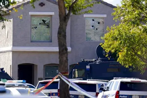 Multiple holes in windows can be seen at a house where five Phoenix Police Department officers were shot and four others were injured after responding to a shooting inside the home Friday, Feb. 11, 2022, in Phoenix. The shooting suspect was found dead in the home following a barricade situation, and a woman at the home was critically injured. (AP Photo/Ross D. Franklin)