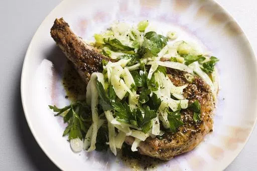 This image released by Milk Street shows a recipe for seared pork chops with fennel and herb salad. (Milk Street via AP)