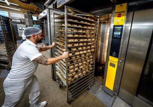 ADDING FULL NAME OF BUSINESS  An employee pushes bread rolls into one of the gas heated ovens in the producing facility in Cafe Ernst in Neu Isenburg, Germany, Monday, Sept. 19, 2022. Andreas Schmitt, head of the local bakers' guild, said some small bakeries are contemplating giving up due to the energy crisis. (AP Photo/Michael Probst)