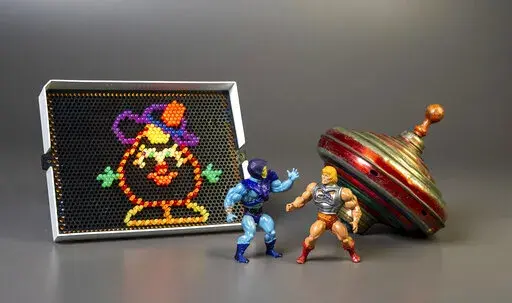 This undated photo provided by The Strong Museum shows the three toys inducted into the National Toy Hall of Fame on Nov. 10, 2022, in Rochester, N.Y. Masters of the Universe, Lite-Brite and the top were chosen from among 12 finalists for the annual honor, which recognizes toys that have inspired creative play and lasting popularity. (Courtesy of The Strong Museum via AP)