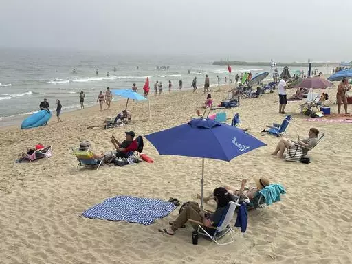 Beachgoers sit on chairs and under umbrellas at Ocean Grove, N.J., beach on Sunday, May 26, 2024. As the temperature heats up and summer approaches, small business owners may be considering offering summer hours, such as an early release on Fridays, for employees to help combat burnout. (AP Photo/Tassanee Vejpongsa, File)