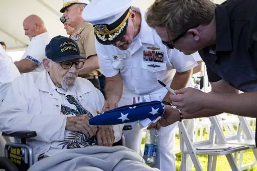 An attendee asks Pearl Harbor survivor Ira "Ike" Schab, 103, to sign an U.S. flag during the 82nd Pearl Harbor Remembrance Day ceremony on Thursday, Dec. 7, 2023, at Pearl Harbor in Honolulu, Hawaii. (AP Photo/Mengshin Lin)