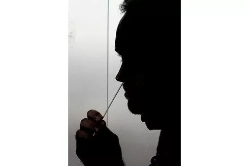 A rapid COVID-19 test is taken, Wednesday, Nov. 18, 2020, in Salt Lake City. President Joe Biden says the federal government will buy half a billion COVID-19 rapid test kits and distribute them free of charge to people to use at home. Delivery of the first batch of the 500 million tests isn't expected until early January 2022. (AP Photo/Rick Bowmer, File)