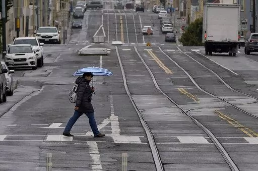A pedestrian carries an umbrella while crossing a street in San Francisco, Thursday, April 14, 2022. A variety of new laws take effect Sunday, Jan. 1, 2023 that could have an impact on people's finances and, in some cases, their personal liberties. (AP Photo/Jeff Chiu, File)