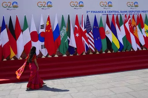 A delegate walks past a display of flags of participating countries at the venue of G-20 financial conclave on the outskirts of Bengaluru, India, Wednesday, Feb. 22, 2023. Top financial leaders from the Group of 20 leading economies are gathering in the south Indian technology hub of Bengaluru to tackle challenges to global growth and stability. India is hosting the G-20 financial conclave for the first time in 20 years. (AP Photo/Aijaz Rahi)