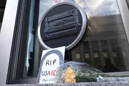 Flowers and a sign are placed outside the headquarters of the U.S. Agency for International Development, or USAID, Feb. 7, 2025, in Washington. (AP Photo/Jose Luis Magana, File)
