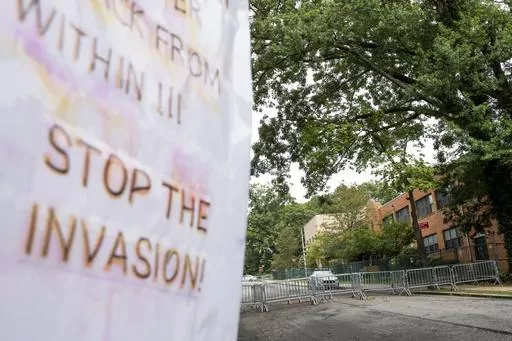 Protest signs are posted outside the former Saint John Villa Academy being repurposed as a shelter for homeless migrants, Wednesday, Sept. 13, 2023, in the Staten Island borough of New York. Scott Herkert, a New Yorker upset that the city has been housing homeless migrants on his suburban block, has set up a loudspeaker to deliver an unwelcoming message in six languages to his new neighbors: "The community wants you to go back to New York City. Immigrants are not safe here." (AP Photo/John Minch