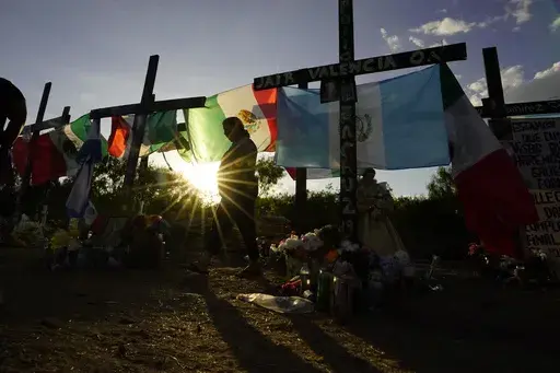 Mourners visit a make-shift memorial to honor the victims and survivors of a human smuggling tragedy in which dozens of migrants were found dead or dying in a tractor-trailer a week prior, July 6, 2022, in San Antonio. (AP Photo/Eric Gay, File)