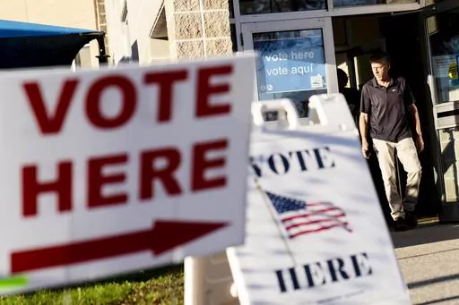 Signs point to the entrance on the last day of early voting before the midterm election as a man walks out of a polling site in Cranston, R.I., on Nov. 7, 2022. Almost half of all voters in the 2022 midterm elections cast their ballots before Election Day either by mail or through early voting, with Asian and Hispanic voters leading the way, new data from the U.S. Census Bureau released Tuesday, May 2, 2023, shows, even as Republican-led states have tightened rules on voting by mail. (AP Photo/D