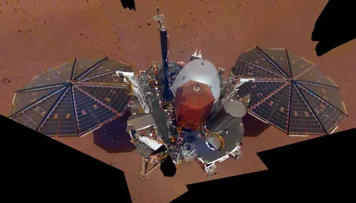 This Dec. 6, 2018 image made available by NASA shows the InSight lander. The scene was assembled from 11 photos taken using its robotic arm. The spacecraft is losing power because of all the dust that's accumulated on its solar panels. NASA said Tuesday, May 17, 2022, it will keep using the spacecraft's seismometer to detect marsquakes until its power peters out. Officials expect operations to cease in July, almost four years after InSight's arrival at Mars. (NASA via AP, File)