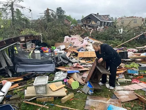 Theresa Haske sorts through debris from what was her garage after a tornado tore through Gaylord, Mich., Friday, May 20, 2022. (AP Photo/John Russell)