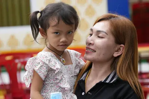 Paweenuch Supolwong, 3, the only child to emerge unscathed from the mass killing attack at the day care center, is held by her mother Anonpai Srithong, 35, during an interview inside Wat Si Uthai temple temple in Uthai Sawan, north eastern Thailand, Saturday, Oct. 8, 2022. A former police officer burst into a day care center in northeastern Thailand on Thursday, killing dozens of preschoolers and teachers before shooting more people as he fled. (AP Photo/Sakchai Lalit)