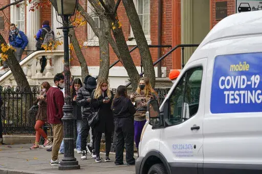 Pedestrians wait in line to get tested for COVID-19 at a mobile testing site near the NYU campus in New York, Thursday, Dec. 16, 2021. (AP Photo/Seth Wenig)