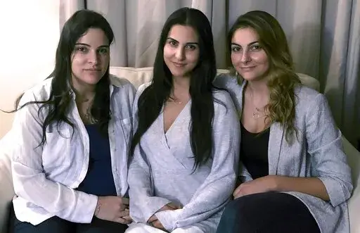 FILE — Three of Amer Fakhoury's four daughters, from left, Guila, Macy, and Zoya Fakhoury, gather Nov. 5, 2019, in Salem, N.H. Amer Fakhoury was a Lebanese American restaurant owner who made his first trip back to Lebanon in 2019 in nearly 20 years to see family. In Lebanon he was accused of torturing and killing inmates at a former prison where his family says he had worked as a clerk. Fakhoury was released in March 2020 and died that August from lymphoma. The Fakhourys are trying to sue Leba