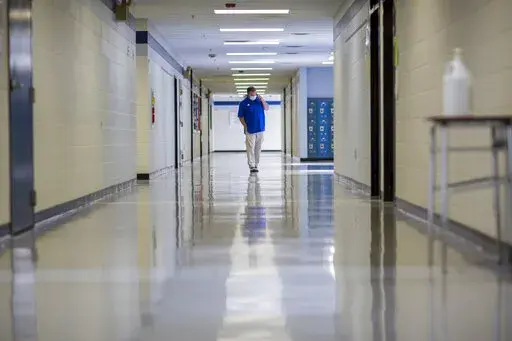 FILE - A middle school principal walks the empty halls of his school as he speaks with one of his teachers to get an update on her COVID-19 symptoms, Friday, Aug., 20, 2021, in Wrightsville, Ga. On Monday, Dec. 27, 2021, U.S. health officials cut isolation restrictions for Americans who catch the coronavirus from 10 to five days, and also shortened the time that close contacts need to quarantine. (AP Photo/Stephen B. Morton, File)