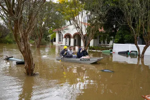 People paddle through a flooded street at Windsor on the outskirts of Sydney, Australia, July 5, 2022. The U.N. weather agency is predicting the phenomenon known as La Nina is poised to last through the end of this year, a mysterious “triple dip” — the first this century — caused by three straight years of its effect on climate patterns like drought and flooding worldwide. (AP Photo/Mark Baker, File)