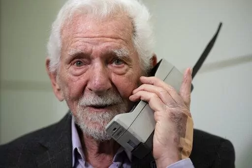 Marty Cooper, the inventor of first commercial mobile phone, poses for the press with a Motorola DynaTAC 8000x, during an interview with The Associated Press at the Mobile World Congress 2023 in Barcelona, Spain, Monday, Feb. 27, 2023. The four-day show kicks off Monday in a vast Barcelona conference center. It's the world's biggest and most influential meeting for the mobile tech industry. (AP Photo/Joan Mateu Parra)