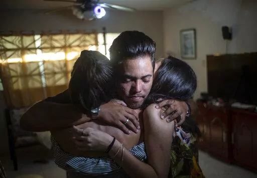 Marcos Marzo hugs two of his friends who came to say goodbye upon receiving the news that he had obtained a permit to travel to the United States, in Havana, Cuba, Wednesday, Jan 25, 2023. Now in the U.S., his dream is to do a master’s degree at the Massachusetts Institute of Technology and work as an engineer, which he says is his passion. (AP Photo/Ramon Espinosa)