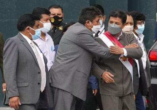 Peru's President Pedro Castillo, right, is embraced by one of his party´s lawmakers as he leaves Congress where lawmakers voted to proceed with impeachment proceedings against him, in Lima, Peru, Monday, March 28, 2022. (AP Photo/Martin Mejia)