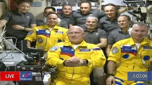 In this frame grab from video provided by Roscosmos, Russian cosmonauts Sergey Korsakov, Oleg Artemyev and Denis Matveyev are seen during a welcome ceremony after arriving at the International Space Station, Friday, March 18, 2022, the first new faces in space since the start of Russia’s war in Ukraine. The crew emerged from the Soyuz capsule wearing yellow flight suits with blue stripes, the colors of the Ukrainian flag. (Roscosmos via AP)
