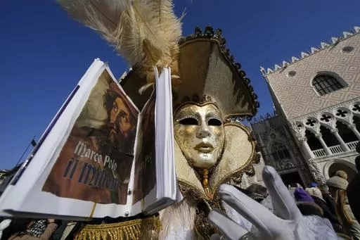 A man wears a mask and holds the replica a the book 'The Million" a report of Marco Polo's travels in Asia, during the Carnival in Venice, Italy, Sunday Jan. 28, 2024. Venice is marking the 700th anniversary of the death of Marco Polo with a yearlong series of commemorations, starting with the opening of Carnival season honoring one of the lagoon city's most illustrious native sons. (AP Photo/Luca Bruno)