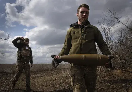Ukrainian soldiers carry shells to fire at Russian positions on the front line, near the city of Bakhmut, in Ukraine's Donetsk region, on March 25, 2024. Ukraine faces twin challenges of fighting Russia and the shifting political sands in the US. (AP Photo/Efrem Lukatsky)